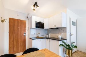 a kitchen with white cabinets and a wooden table at Apartament Oławska in Wrocław