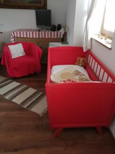 - un lit bébé rouge avec un ours en peluche dans l'établissement Míves Vendégház, à Pogány