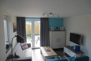 a living room with a couch and a tv at Luxe vakantiewoning dicht bij strand in Zoutelande