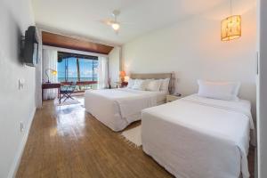 a hotel room with two beds and a television at Arraial D'ajuda Eco Resort in Arraial d'Ajuda