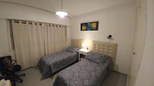 1 dormitorio con 2 camas y mesa con lámpara en San Martin 900 con estacionamiento en Cipolletti