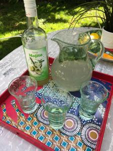 a table with glasses and a bottle and a vase at La maison de Concise - non adapté pour les enfants ni pour les mariages in Thonon-les-Bains