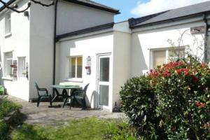 a house with a patio with a table and chairs at Taffs Well Cottage in Taffs Well