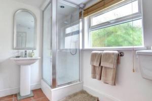 uma casa de banho com um chuveiro, um lavatório e um espelho. em Taffs Well Cottage em Taffs Well