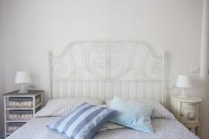 un letto con testiera bianca e due comodini di Sirena Apartment a Riccione