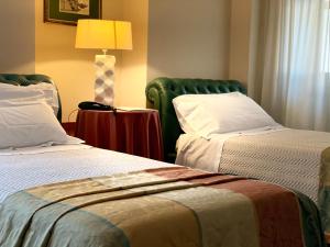una camera d'albergo con due letti e una lampada di Hotel Villa Traiano a Benevento
