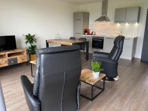 a living room with black chairs and a kitchen at Hof van Lenthe appartement De Bosrand in Dalfsen