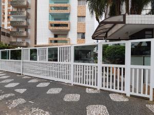 ein weißer Zaun vor einem Gebäude in der Unterkunft APARTAMENTO EM SÃO VICENTE - SP in São Vicente