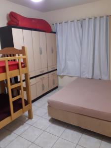 um quarto com uma cama e armários e uma janela em APARTAMENTO EM SÃO VICENTE - SP em São Vicente
