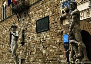 two statues of men standing next to a brick building at Crystal Ship Apartments in Florence