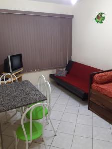 um quarto com uma cama, uma mesa e uma televisão em APARTAMENTO EM SÃO VICENTE - SP em São Vicente