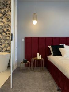 una camera con una testiera rossa e un letto con due tavoli di IVY Apartament a Varsavia