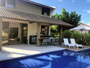 eine Terrasse mit einem Tisch und Stühlen neben einem Pool in der Unterkunft Bangalô Luxo Malawi Beach Houses in Porto De Galinhas