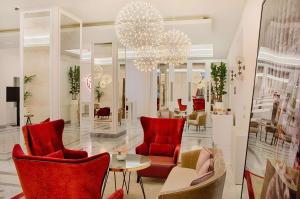 a lobby with red chairs and a table and a chandelier at NH Collection Palazzo Cinquecento in Rome