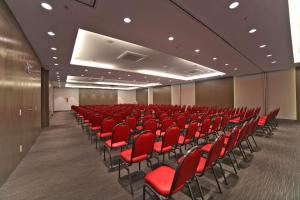an empty conference room with red chairs in it at NH Collection Curitiba in Curitiba