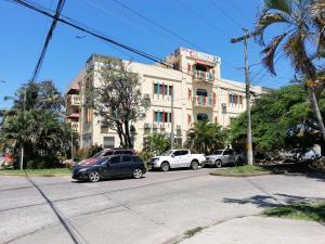 un edificio con coches estacionados frente a él en Hotel Carnaval, en La Ceiba