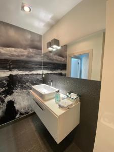 a bathroom with a sink and a painting of the ocean at Apartament 37 Playa Baltis przy plaży in Międzyzdroje