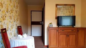 a room with a television on a dresser with a table at Villa Bri in Łeba