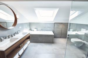 a bathroom with a sink and a toilet and a mirror at Sonnhof - Luxus Alpine Penthouse in Bad Wiessee