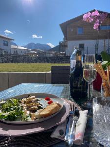 Luxury Unique Homes: Chalets Inzell في انزل: طبق من الطعام على طاولة مع كؤوس النبيذ