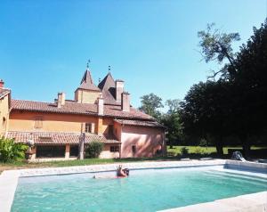 a couple in a swimming pool in front of a house at Château de la Venerie in Denicé