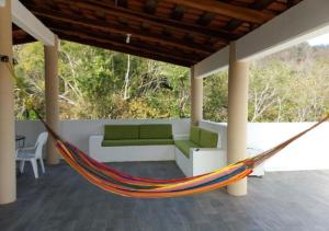 a hammock in a porch with a couch and a table at La Vivienda Villa in Santa Cruz Huatulco