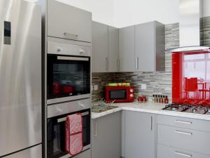 プリマスにあるOne Caprera Guest Houseのキッチン(白いキャビネット、赤い冷蔵庫付)
