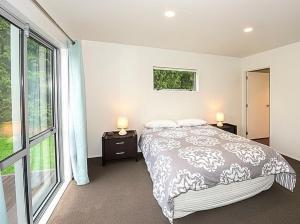 1 dormitorio con cama y ventana grande en Alta House - Ohakune Holiday House, en Ohakune