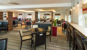 a restaurant with tables and chairs and a bar at Holiday Inn Express Bristol Filton, an IHG Hotel in Bristol