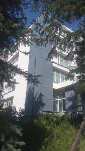 biały budynek z drzewami przed nim w obiekcie Apartament 5 przy Parku Leśnym w Polanicy Zdroju