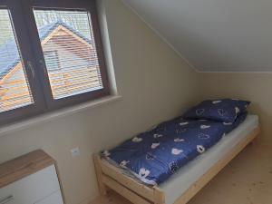 - un petit lit dans une chambre avec 2 fenêtres dans l'établissement OSADA CZTERY PORY ROKU - DOM JESIEN, à Kopalino