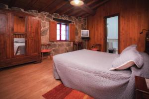 - une chambre avec un lit et un mur en pierre dans l'établissement Casa Baralló, à Lobios