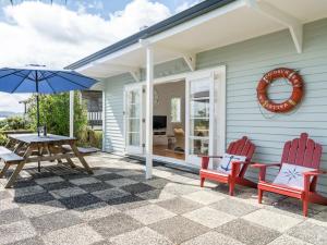 een patio met een tafel en stoelen en een parasol bij Blue Peter - Opua Holiday Home in Opua