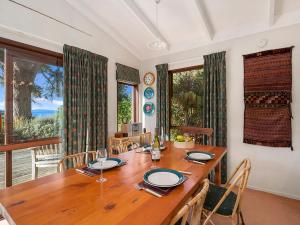 a dining room with a wooden table and a large window at Ruatotara - Pukawa Holiday Home in Kuratau +11 photos