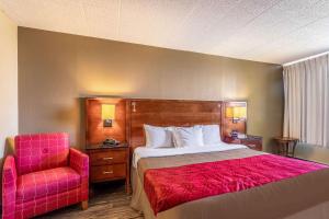 a bedroom with a bed and a red chair at Econo Lodge in Fredonia