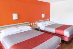 2 camas en una habitación con paredes de color naranja en Rodeway Inn Altoona, en Altoona