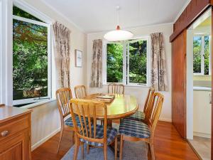 uma sala de jantar com mesa, cadeiras e janelas em Te Kopua - Acacia Bay Holiday Home em Taupo