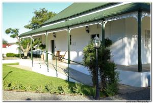a house that has a porch and some trees at Victorian Square Guesthouse in Graaff-Reinet
