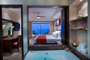 プエルト・バジャルタにあるSunset Plaza Beach Resort Puerto Vallarta All Inclusiveのバスタブ付きのホテルルームとベッドルーム1室が備わります。