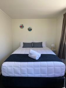 a bedroom with a large white bed with a blue blanket at Takapuna Beach Holiday Park in Auckland