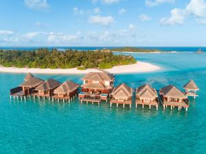 a beach area with a beach house and a boat on the water at Anantara Dhigu Maldives Resort in Gulhi