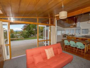 sala de estar con sofá naranja y mesa en Sixties Cedar Bach - Kuratau Holiday Home, en Kuratau