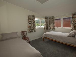 a bedroom with two beds and two windows at Sixties Cedar Bach - Kuratau Holiday Home in Kuratau
