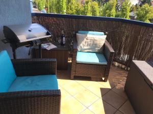a patio with two chairs and a grill on a balcony at Apartament 4 You in Swarzędz