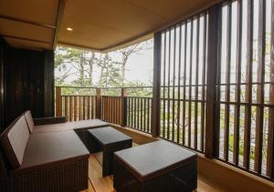 a balcony with a table and benches and windows at Awaji Hamarikyu Takumi in Minamiawaji