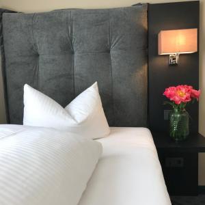 Un dormitorio con una cama blanca y un jarrón de flores en ROSS Hotel en Stuttgart