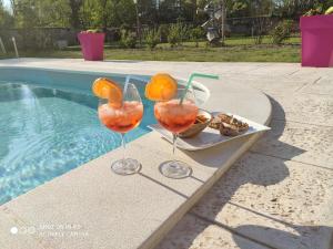 dos copas de vino sentadas en una mesa junto a una piscina en L'Amalgam', en Ainay-le-Vieil