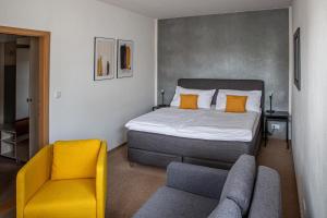 ein Schlafzimmer mit einem Bett und einem gelben Stuhl in der Unterkunft Penzion Dena in Jihlava