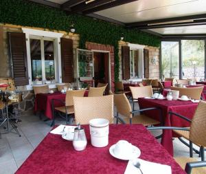 リーヴァ・デル・ガルダにあるAlbergo Garni Orchideaの赤いテーブルクロスのテーブルと椅子が備わるレストラン