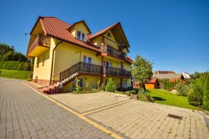 a large yellow house with a brick driveway at Dworek Julia in Polańczyk